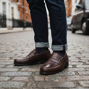 Mocassins penny loafer Pellet en cuir brun portés avec un jean brut dans une rue pavée, style moodeshop preppy.