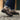 Chaussure oxford cuir marron avec semelle crantée, portée sur rue pavée en lumière naturelle