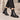 Bottines Chelsea moodeshop noires en cuir artisanal avec semelle en gomme, portées sur des marches en pierre