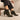 Femme portant les Chelsea boots Rikley en suède vert mousse, assise dans un fauteuil designer moderne
